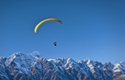 Image of a yellow paraglider above the mountains